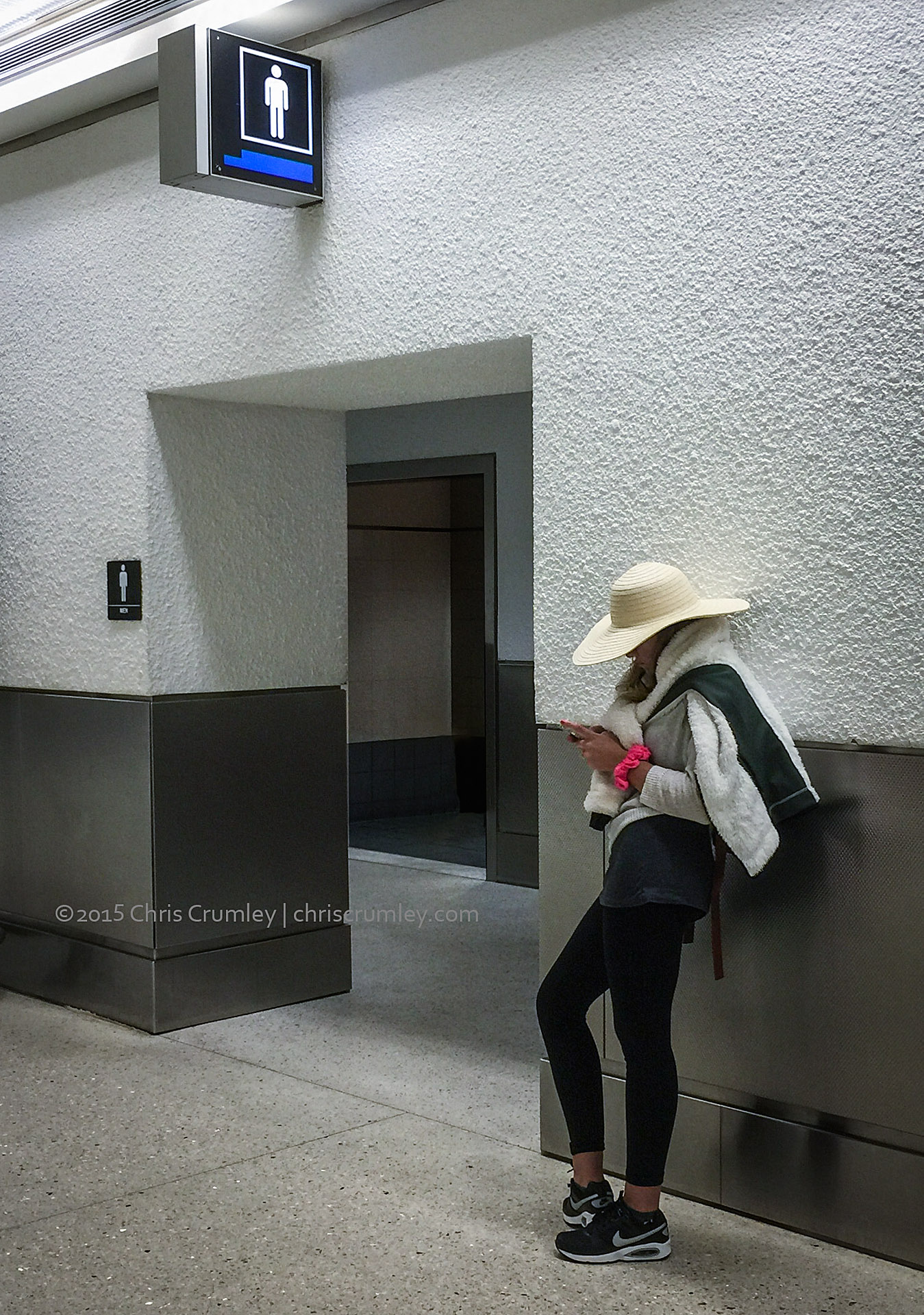 Miami Airport; Woman waiting outside Men's restroom